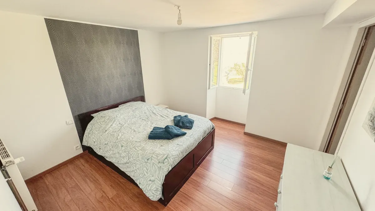 Une chambre double au parquet de bois, lit fait et serviettes posées