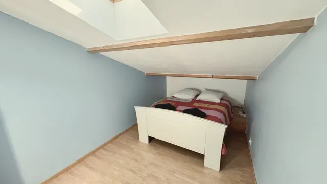 Une chambre aux murs bleu clair sous la verrière