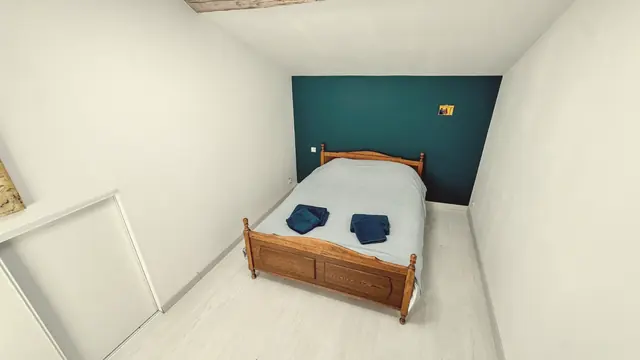 Une chambre au mur bleu nuit et au lit en bois