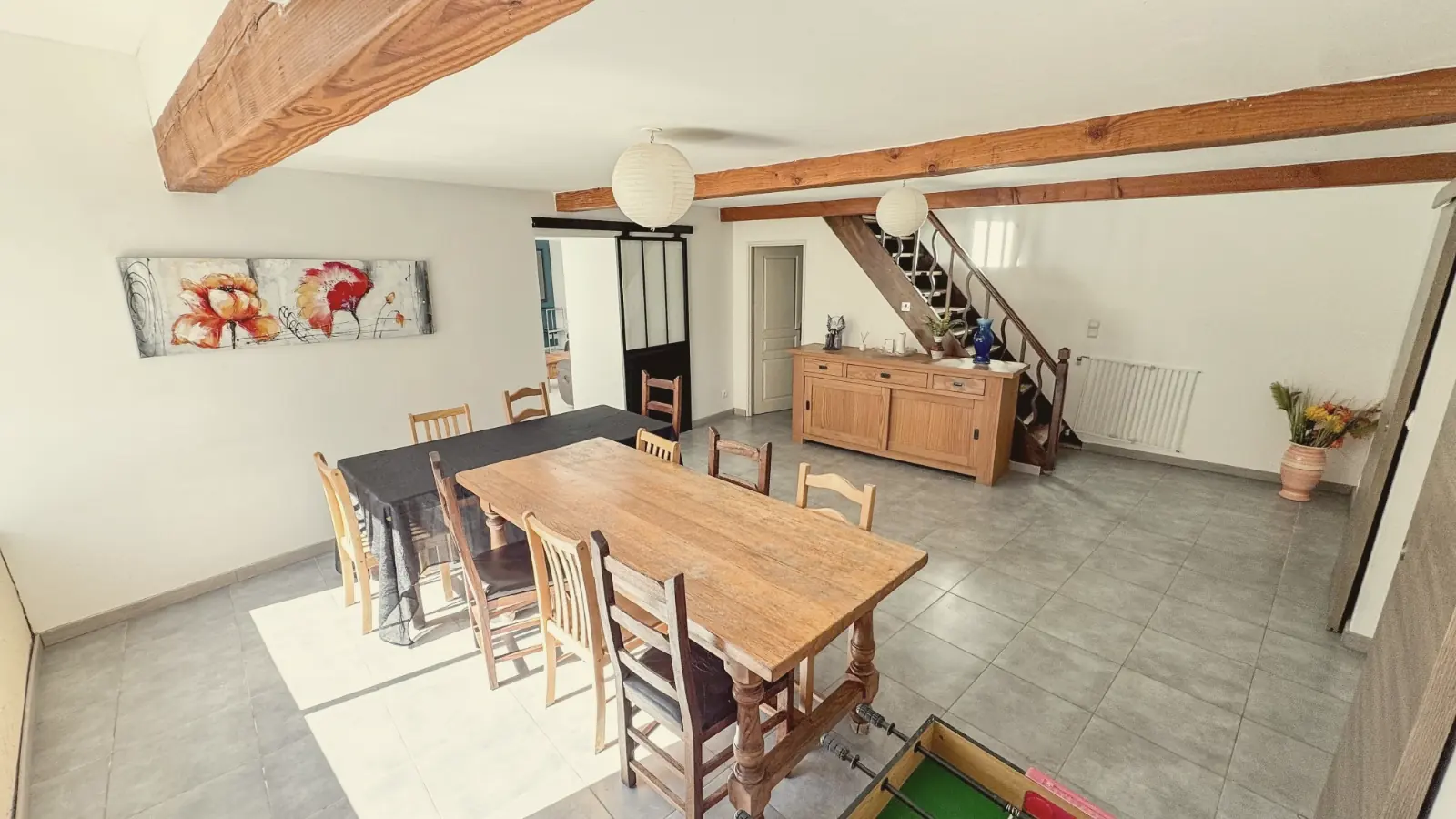 La salle à manger et sa grande table en bois sous les poutres